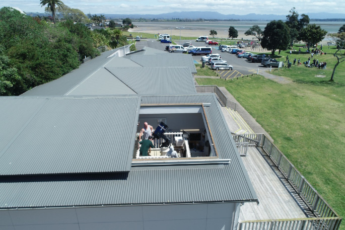 The TAS observatory's open sliding roof at Fergusson Park, with people gathered around a telescope